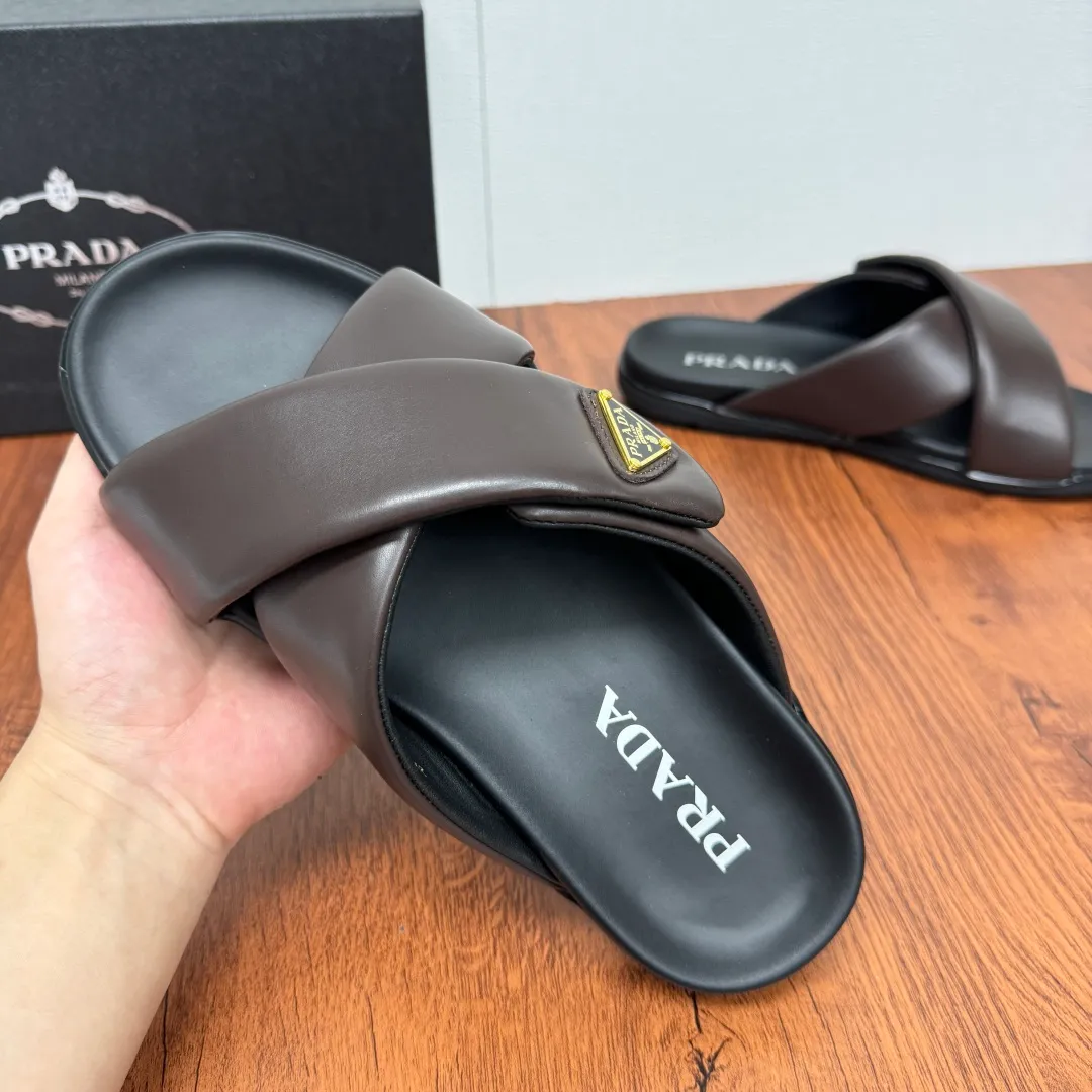 Batch 580 Prada/Prada's new men's leather cross slippers. Velcro closure can finely adjust the size. Calf leather light luxury slippers. Thick soft calf leather wraps the upper. Fat but soft rubber lazy style, soft and comfortable, excellent foot feel. Genuine leather bottom layer, cross style, with a Velcro closure buckle, easy to adjust the appropriate size, and a perfect fit for the wearing experience. The enamel gold triangle logo highlights the brand's classic features. Lightweight rubber thin sole, high foot comfort! Complete package! Size: 39-40-41-42-43-44-45 Leather shoe size Item number: 2X7132 Brown
